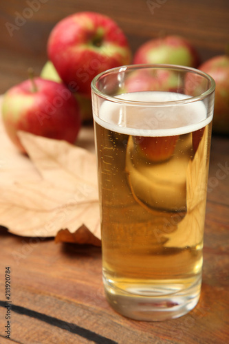 Apple cider in a glass on a brown wooden background.