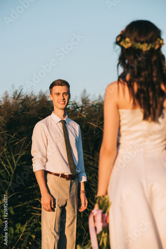 smiling young groom looking at beautiful bride with wedding bouquet