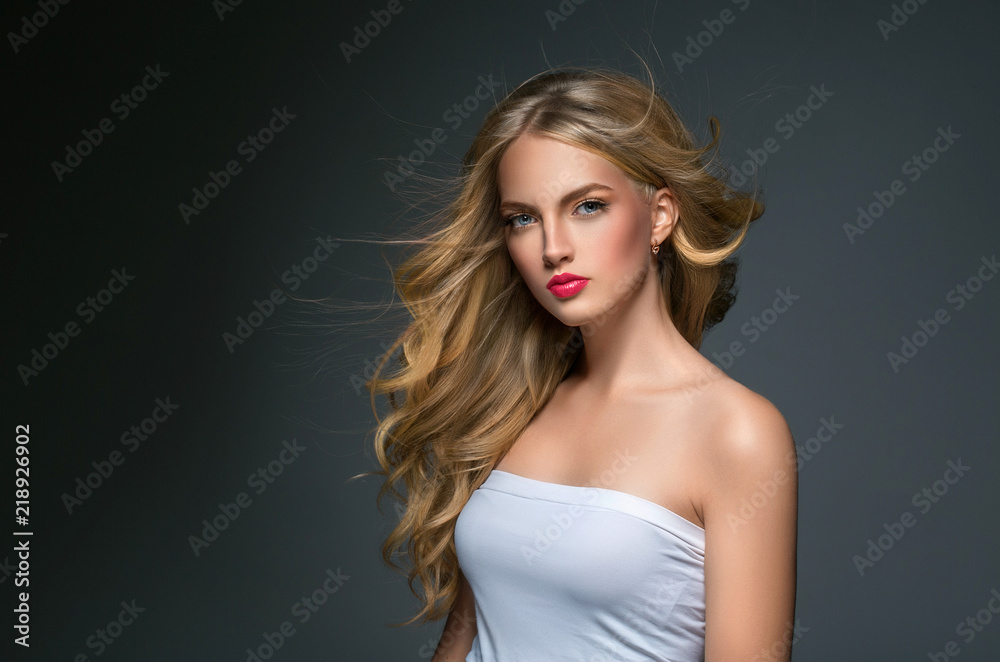 Blonde hairstyle woman beauty with long curly blonde hair over dark background Blonde hairstyle woman beauty with long curly blonde hair over dark background