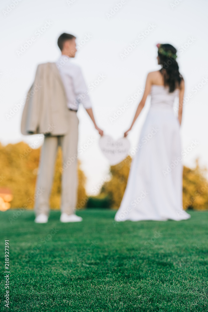 selective focus of young wedding couple standing together on green lawn