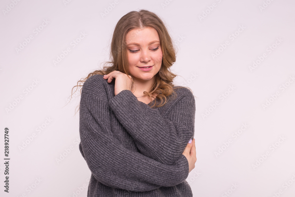 Portrait of fashionable young woman with curly hair in grey cardigan on white background