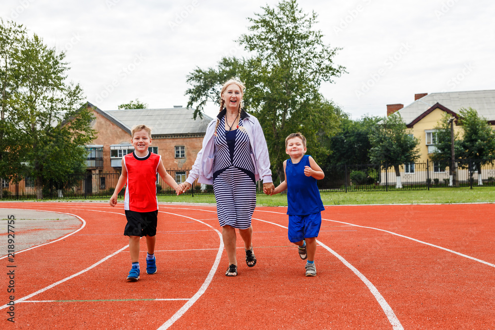 Obraz premium young grandmother runs a sports stadium with the grandkids