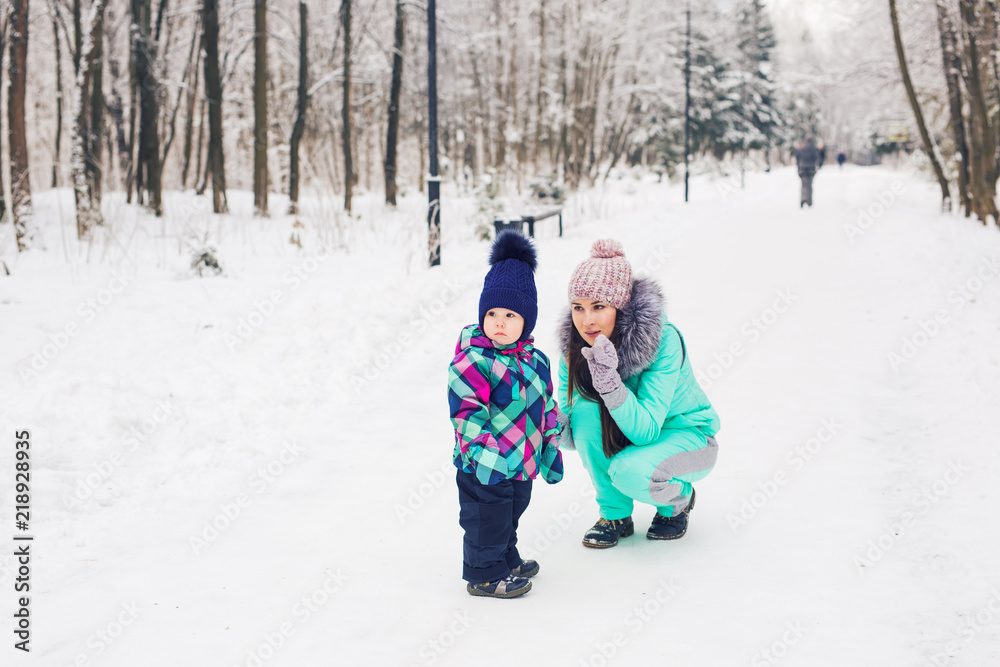 Winter, parents and children concept - mother and daughter walking and having fun on a snowy street