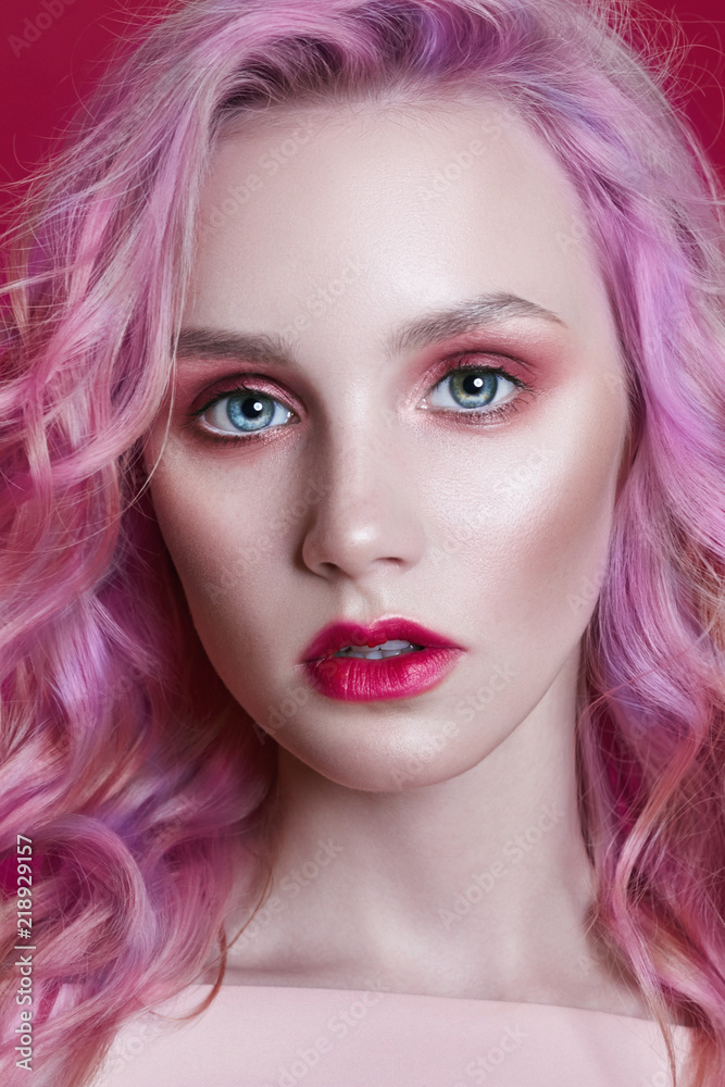 Fototapeta premium Portrait of a woman with bright colored flying hair, all shades of pink purple. Hair coloring, beautiful lips and makeup. Hair fluttering in the wind. Sexy girl with long hair