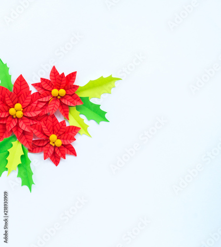 Paper flower poinsettia and leaves of holly