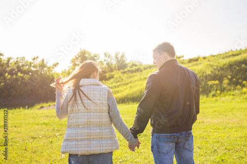 Rear view of couple holding hands together and walking in autumn countryside