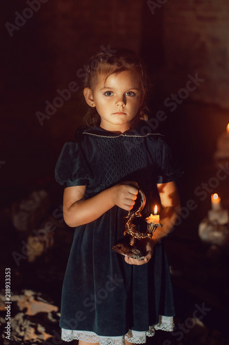 Сhild with candles in hands. Nightmare for children. Lost sad little girl in dark.
