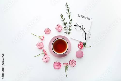 Rose flowers with cup of tea and macaron on white background