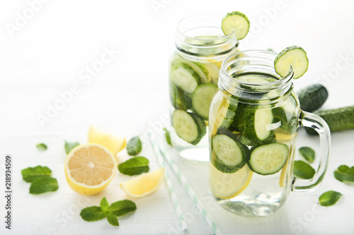 Lemonade with cucumbers, lemons and mint leafs in glass jars on wooden table