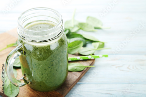 Spinach smoothie in glass jar on wooden table
