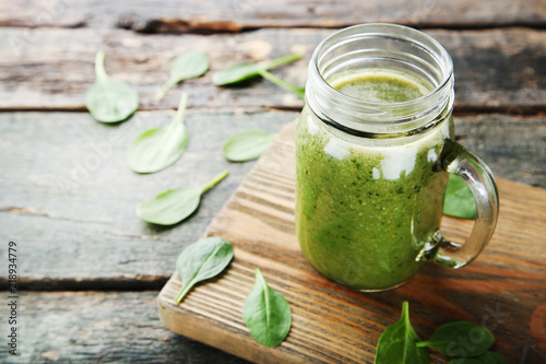 Spinach smoothie in glass jar on grey wooden table