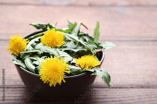 Fototapeta Naklejka Na Ścianę i Meble -  Yellow dandelions in bowl on wooden table