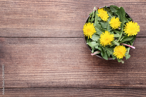Fototapeta Naklejka Na Ścianę i Meble -  Yellow dandelions in bowl on brown wooden table