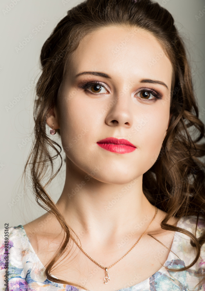 young elegant woman with professional hairstyle poses on a gray background. young elegant woman with professional hairstyle poses on a gray background.