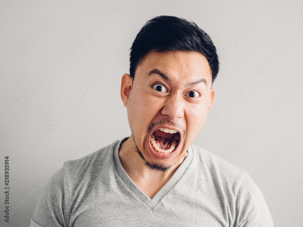 Headshot photo of Asian man with angry and furious face. on grey background. Headshot photo of Asian man with angry and furious face. on grey background.