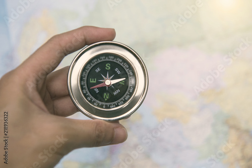 Hand holding magnetic compass and world map. concept adventure of global travel.