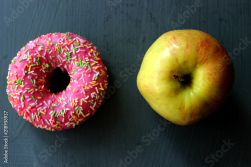 Donut and apple healthy food choices on wooden board, The concept of choosing the right food, diet