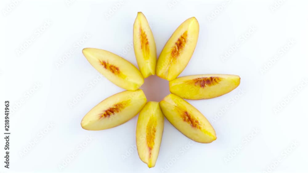 Ripe peach fruit sections. Top view from above of peach slices forming a star shape. Rotating on the turntable isolated on the white background. Close up. Macro. Ripe peach fruit sections. Top view from above of peach slices forming a star shape. Rotating on the turntable isolated on the white background. Close up. Macro.
