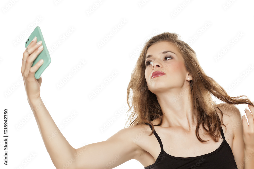 Portrait of young happy beautiful woman with long curly hair taking selfies on white background Portrait of young happy beautiful woman with long curly hair taking selfies on white background