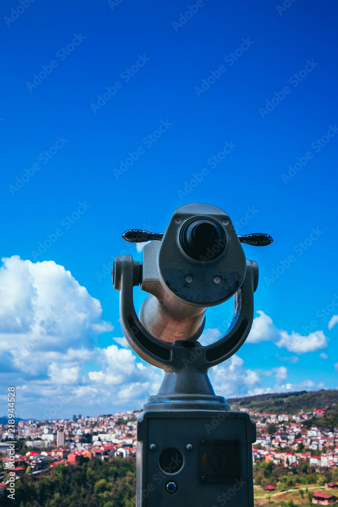 Abstract observation telescope, panoramic view of the abstract european city with red roofs, summer time.