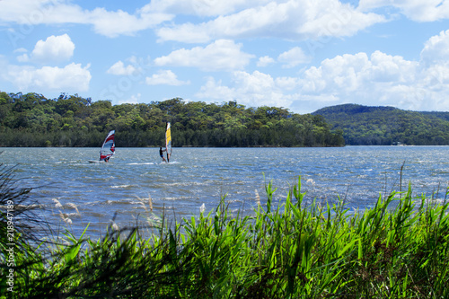 Two windsurfers struggling with a strong wind on Narrabeen Lagoon in Sydney.