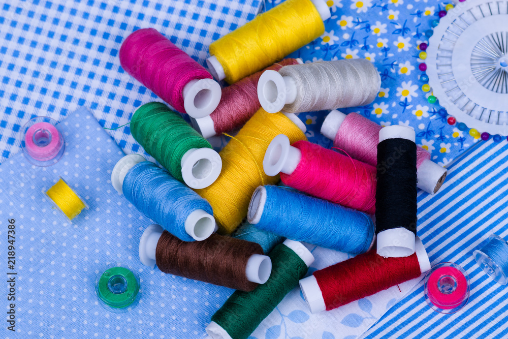 Multicolored threads, buttons on blue fabric Multicolored threads, buttons on blue fabric