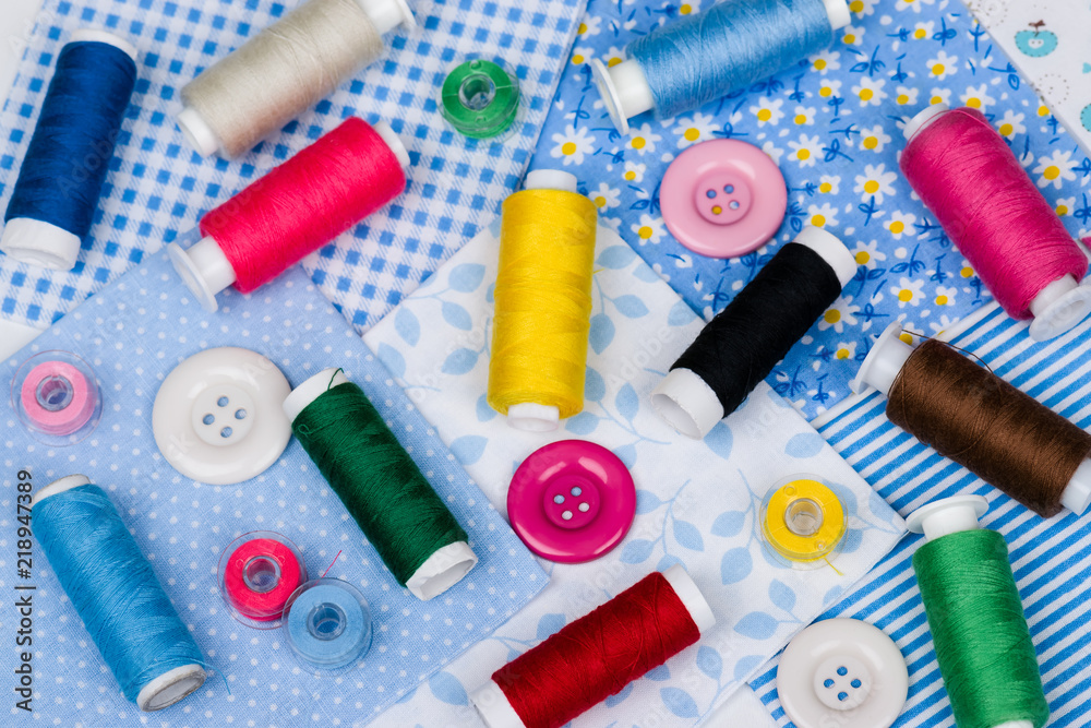 Multicolored threads, buttons on blue fabric Multicolored threads, buttons on blue fabric