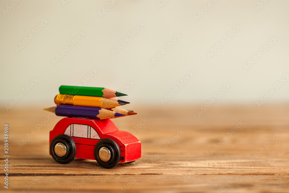 Miniature Red Car Carrying a colorful pencils on wooden table. Back to school concept Miniature Red Car Carrying a colorful pencils on wooden table. Back to school concept