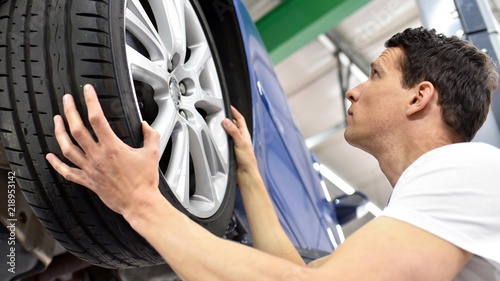 Reifenwechsel in einer autowerkstatt // tyre change in a car repair shop - worker assembles rims on the vehicle photo