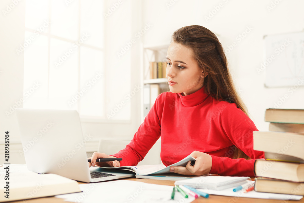 Student girl studying at table full of books Student girl studying at table full of books