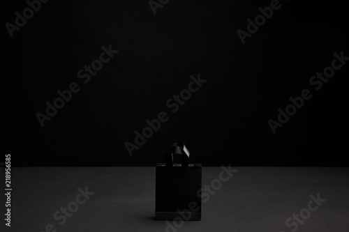 close up view of black paper shopping bag on black background