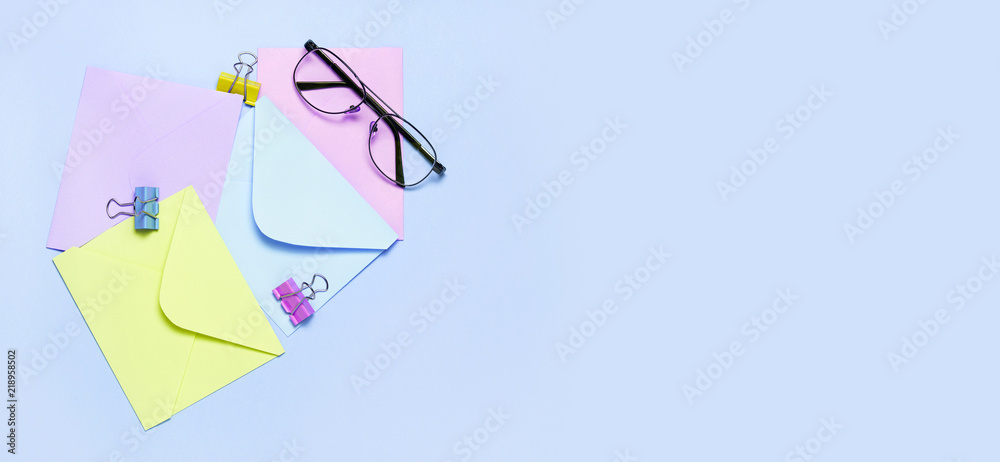 Frame from colorful envelopes and eye glasses on blue table top view. Flat lay, copyspace for your text