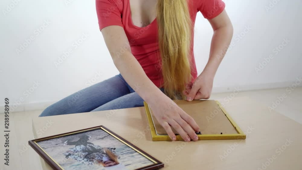 Family photo wall decor. Young girl putting family photograph in a frame. Family photo wall decor. Young girl putting family photograph in a frame.