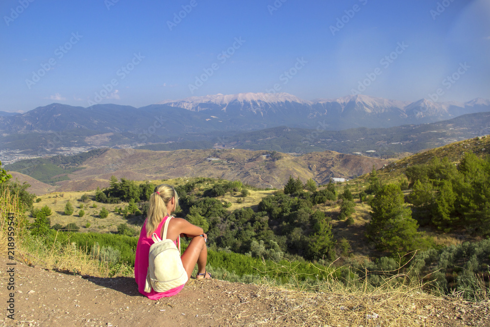 Photos Young woman sitting at edge of cliff looking over expansive view of plains and m