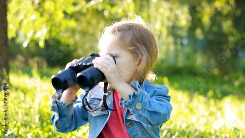 Child girl looking through binoculars and watching the nature
