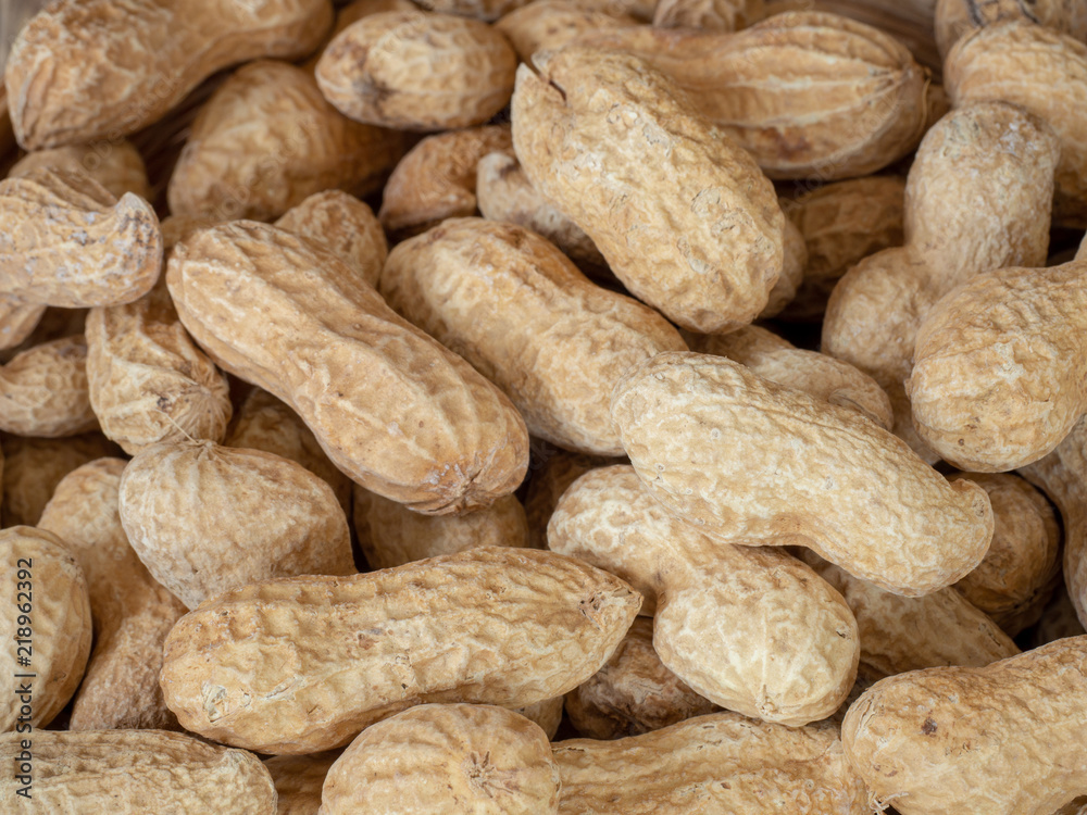Closeup dried peanuts in shells on peanuts background on wooden table. Concept of snack Closeup dried peanuts in shells on peanuts background on wooden table. Concept of snack