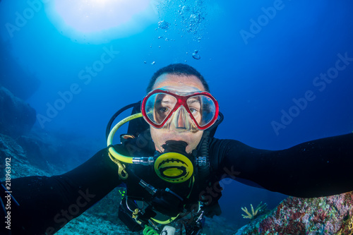 A SCUBA diver exploring a dark tropical coral reef