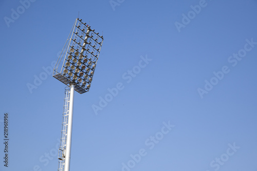 Sports light pole or Stadium Light tower in sport arena on blue sky with clouds. photo