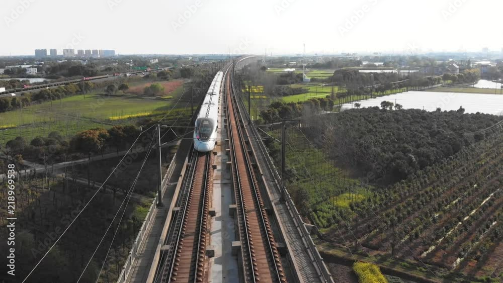 Raised high speed rail train passes. China's bullet train CSR zooming through the rural countryside. 