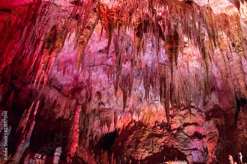 old stalactites on the ceiling of the cave in pink light