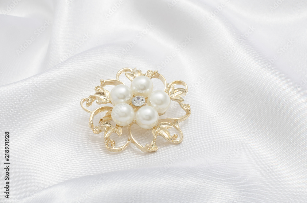 gold brooch flower with pearl on silk background gold brooch flower with pearl on silk background