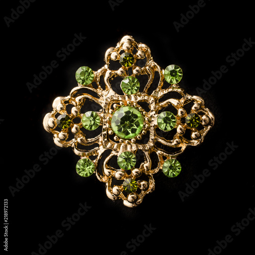 gold brooch with emeralds isolated on black