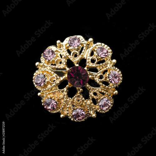 gold round brooch with purple diamonds isolated on black