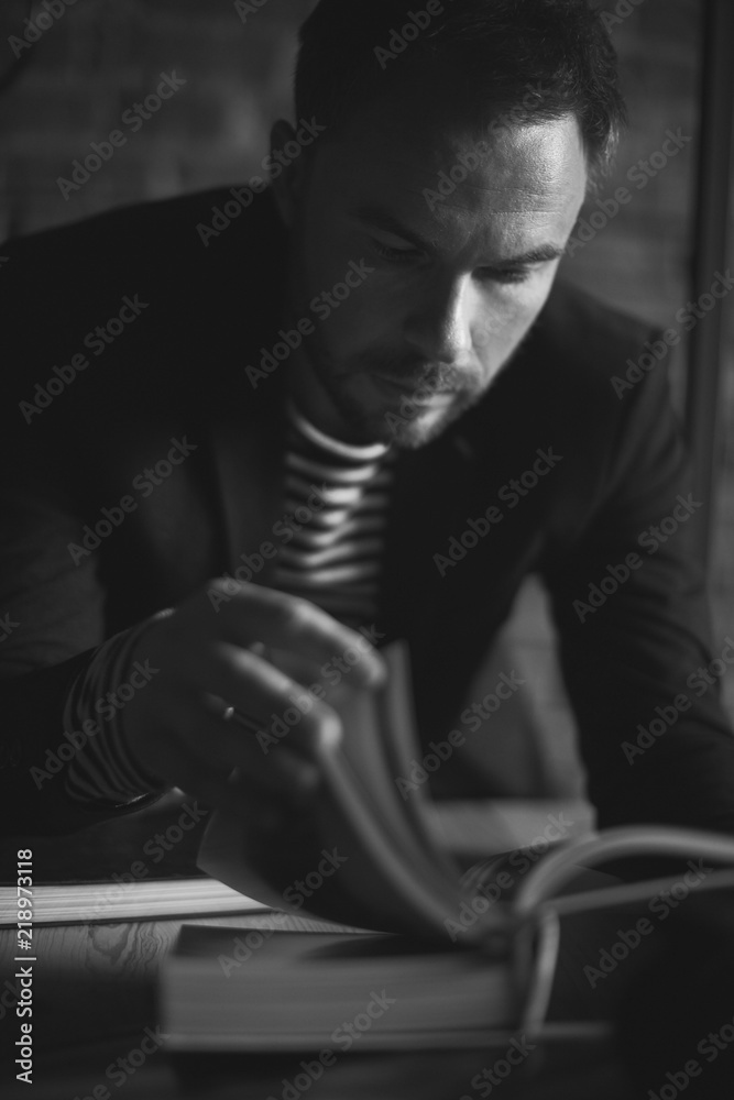 Black and white portrait of handsome stylish man in jacket. Man reading the book.
