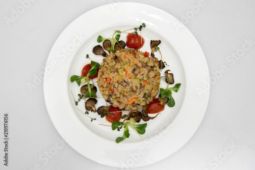 rice with mushrooms. a dish of rice on a white plate. porridge of rice with champignons and cherry tomatoes.