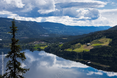 A landscape with  mountains and clouds reflecting in calm water.