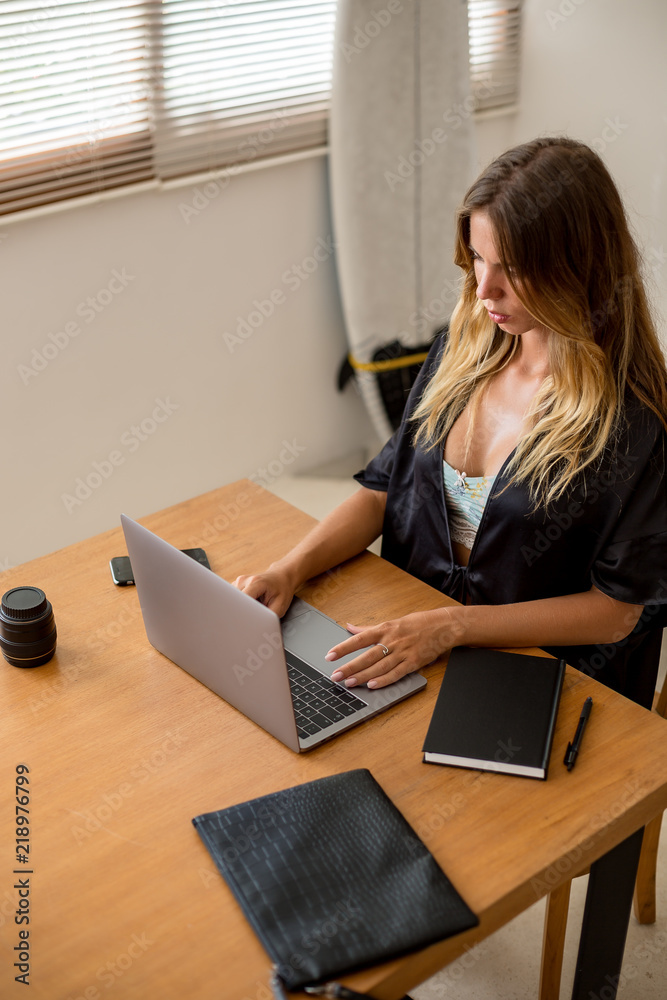 Beautiful young surfer woman in sexy black pajamas work with laptop at  home. Happy girl working online, study and learn with notebook computer.  Modern business lady, freelance work from home concept. Stock