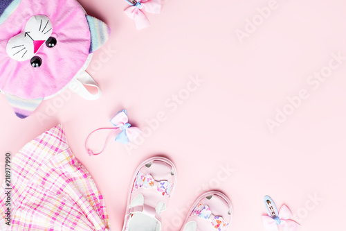Little girl clothes and accessories on pink background.