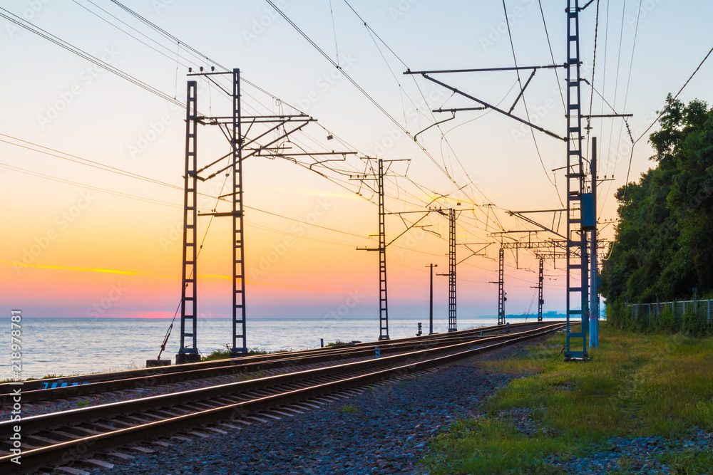 Beautiful landscape of a railroad and towers of traction line on the background of the sea at twilight, Sochi, Russia
