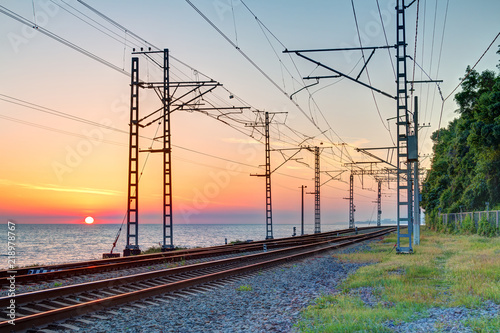 Beautiful landscape of a railroad and towers of traction line on the background of the sea at sunset, Sochi, Russia
